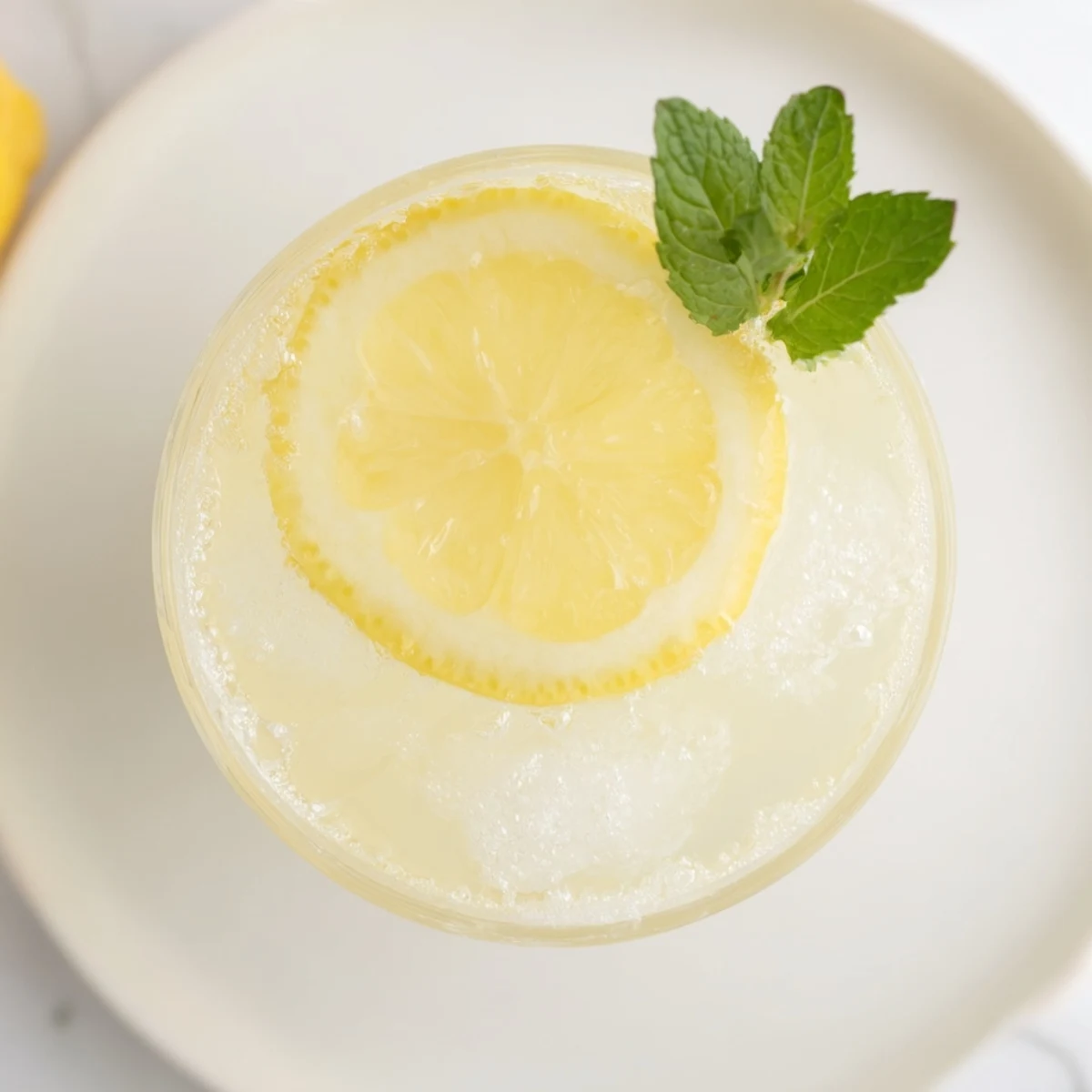Bright yellow Lemon Squeeze, a refreshing summer drink, garnished with lemon slices and mint.