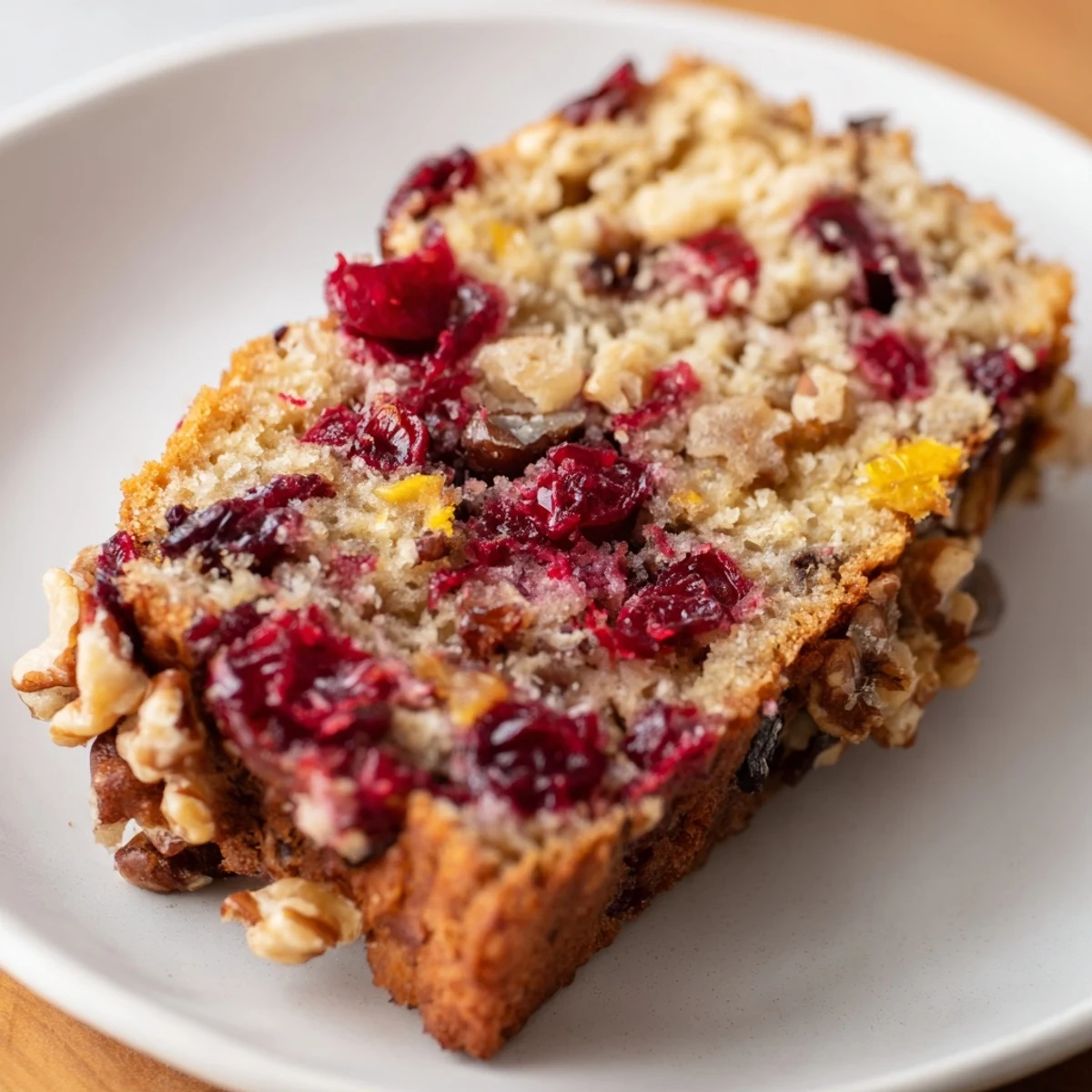 Warm Cranberry Walnut Bread showing a cross-section with visible cranberries and walnuts.