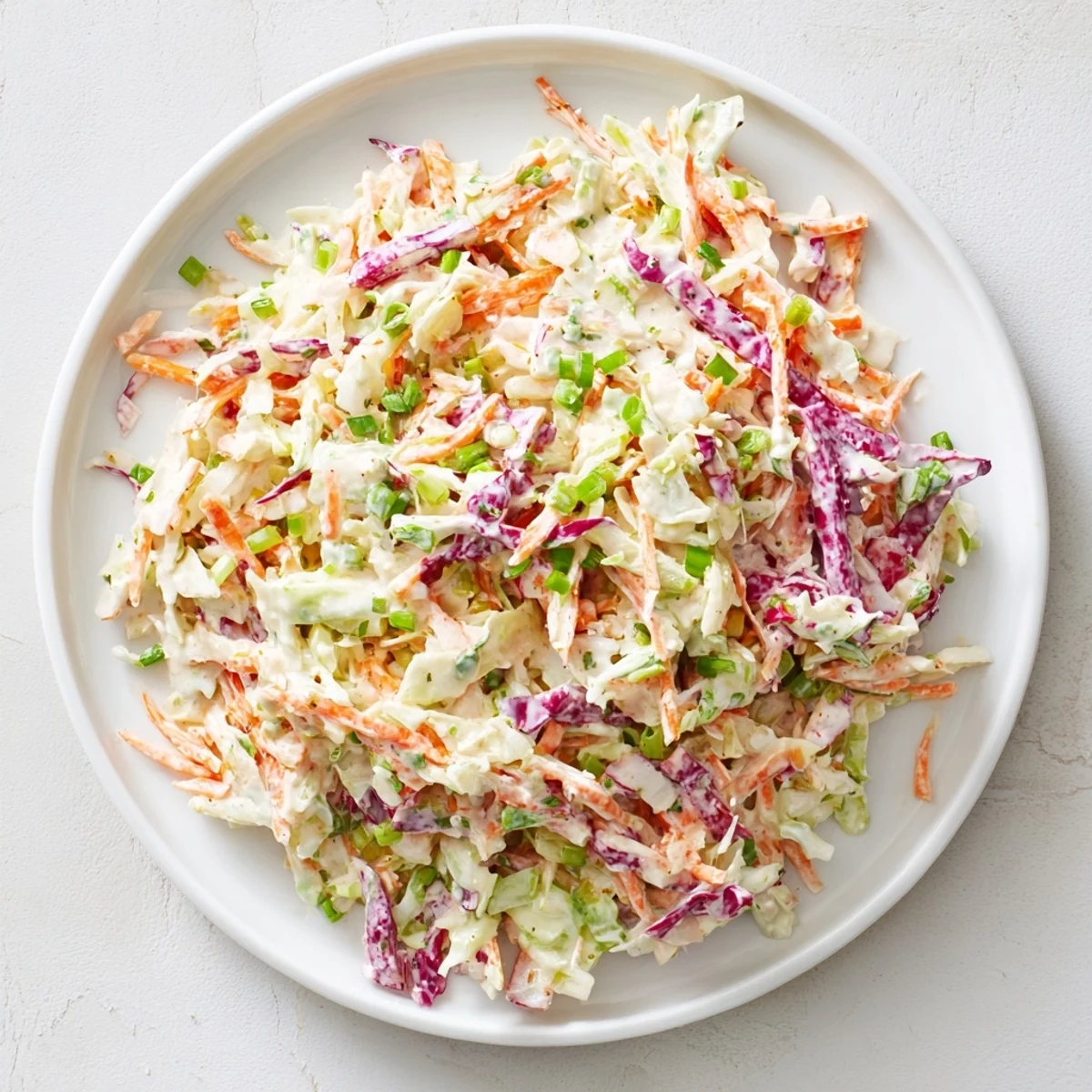 Delicious creamy coleslaw salad with shredded cabbage and carrots, perfect for a summer picnic.