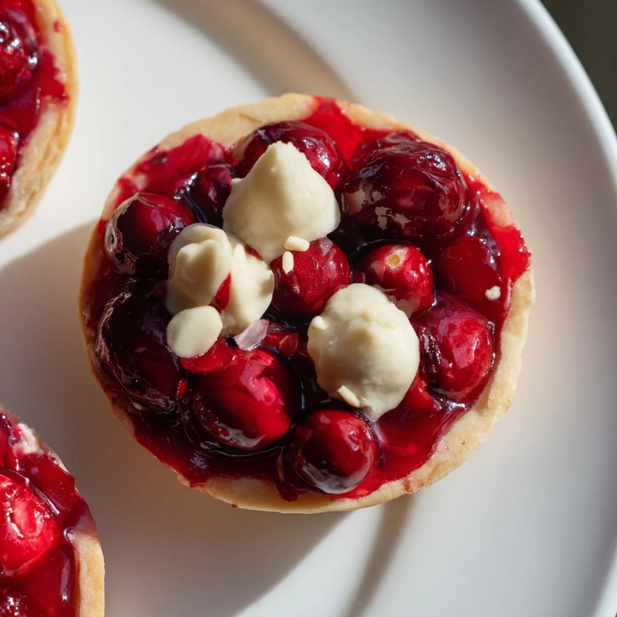 Golden-brown Cranberry Tartlets with a vibrant cranberry filling, fresh from the oven, offering sweet tastes.