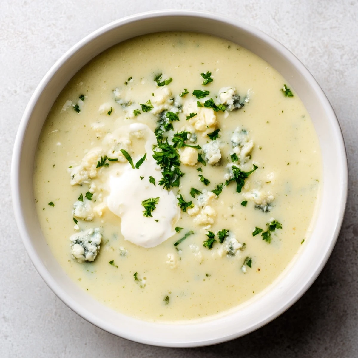 A steaming bowl of Creamy Celery and Stilton Soup, garnished with crumbled blue cheese.