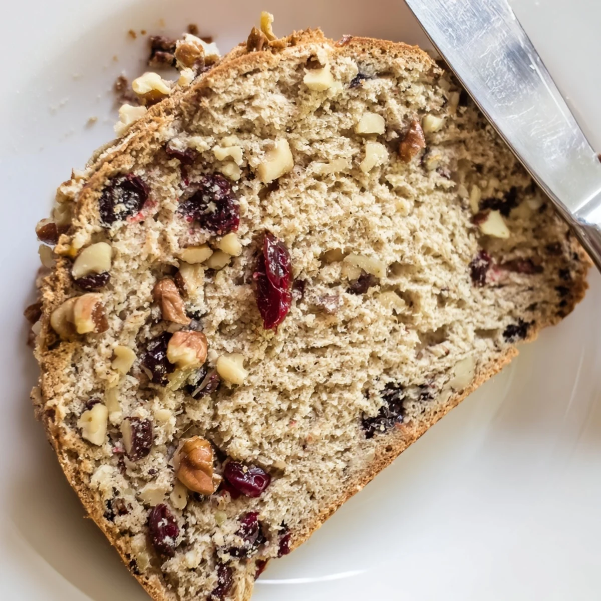 Golden-baked Cranberry and Walnut Soda Bread on a wooden board, with a pat of butter melting into the warm crumb.