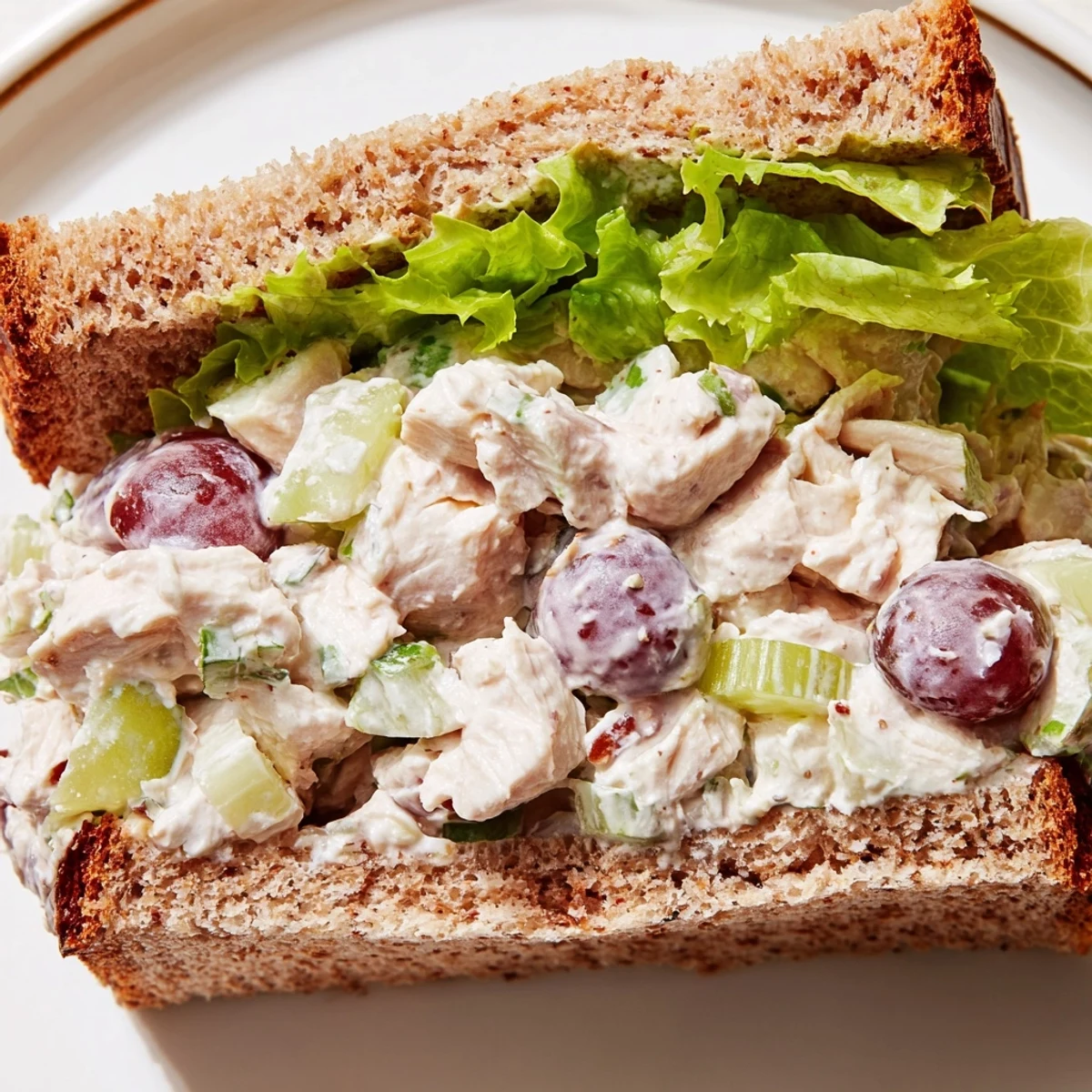 Toasted whole wheat Chicken Salad Sandwich with Grapes and fresh lettuce, served with potato chips for a classic American lunch.