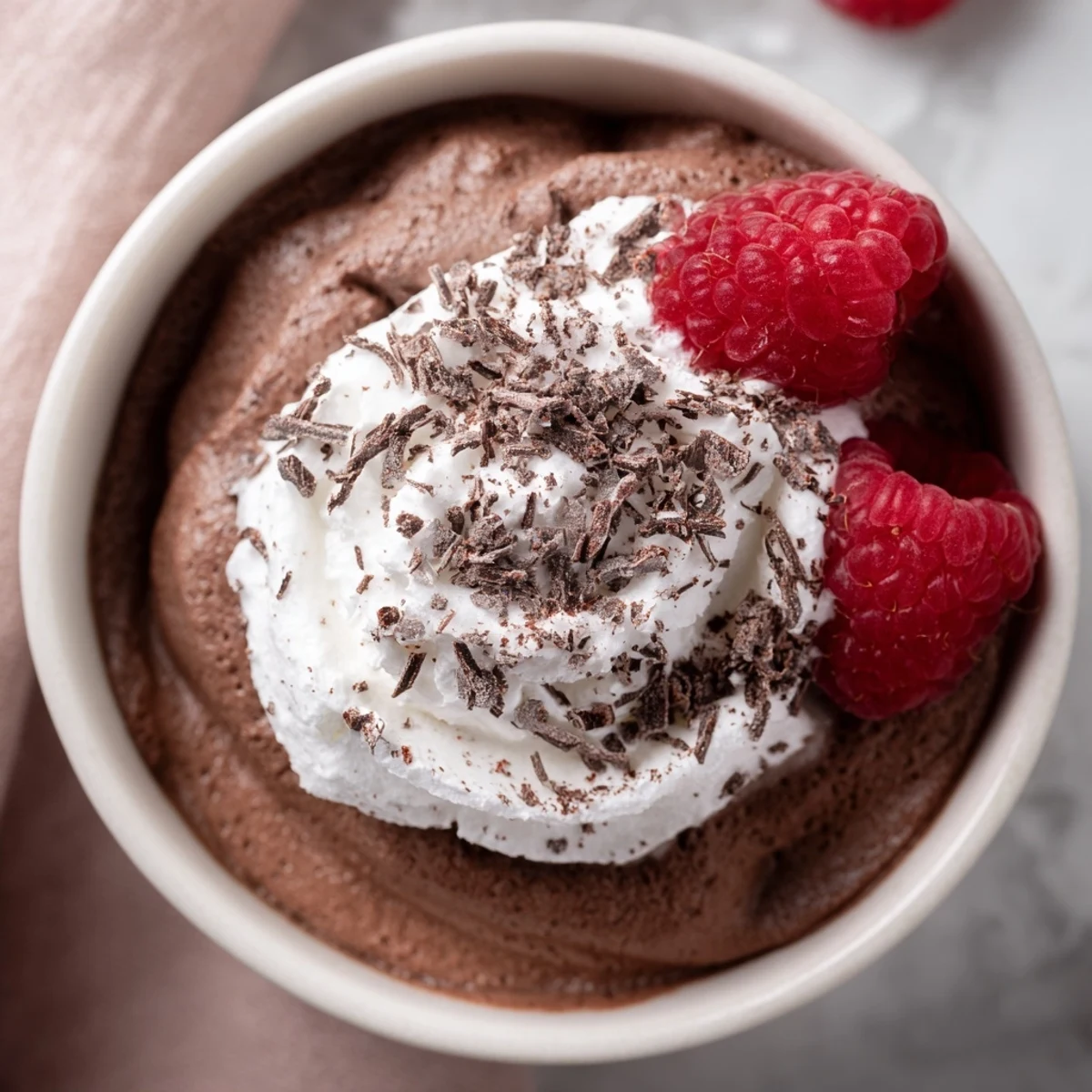 Four glasses of layered Chocolate Lunch Dessert topped with fresh raspberries and a dusting of cocoa powder.