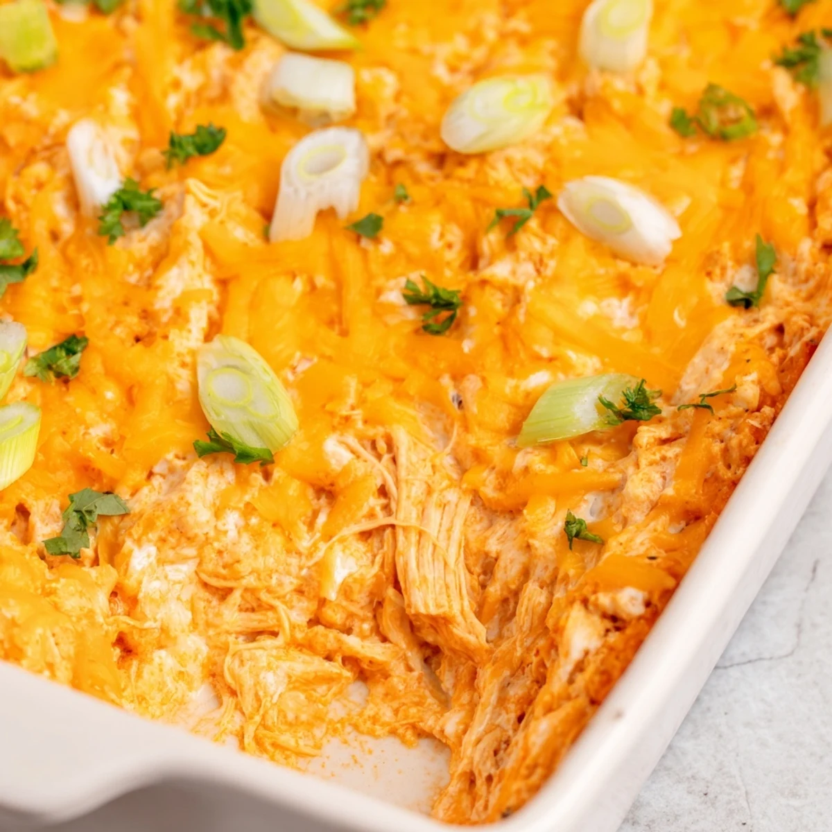 Golden, bubbly Spicy Buffalo Chicken Dip in a baking dish, garnished with green onions and served with crispy tortilla chips.