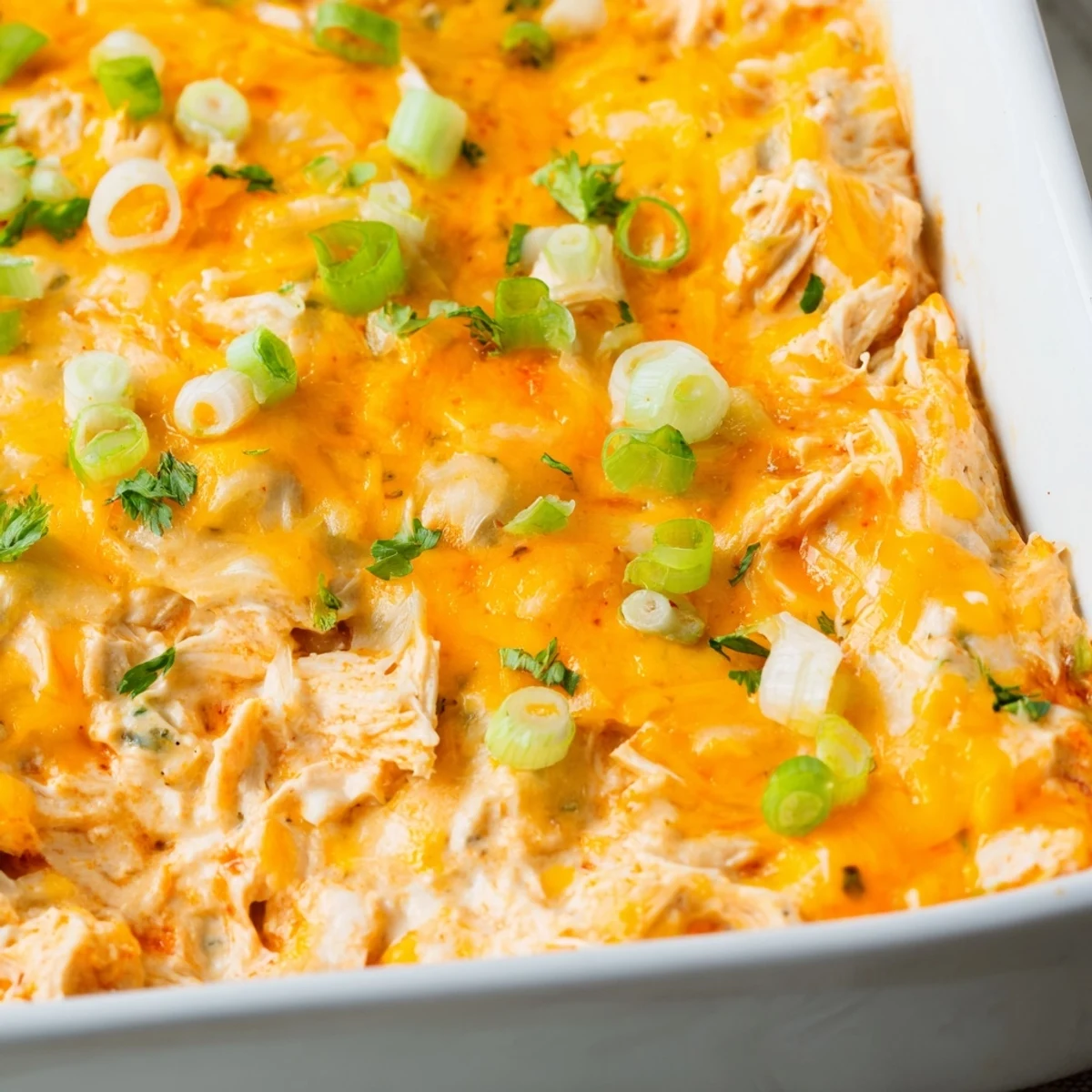 Freshly baked Spicy Buffalo Chicken Dip topped with parsley and green onions, paired with a bowl of crunchy tortilla chips.