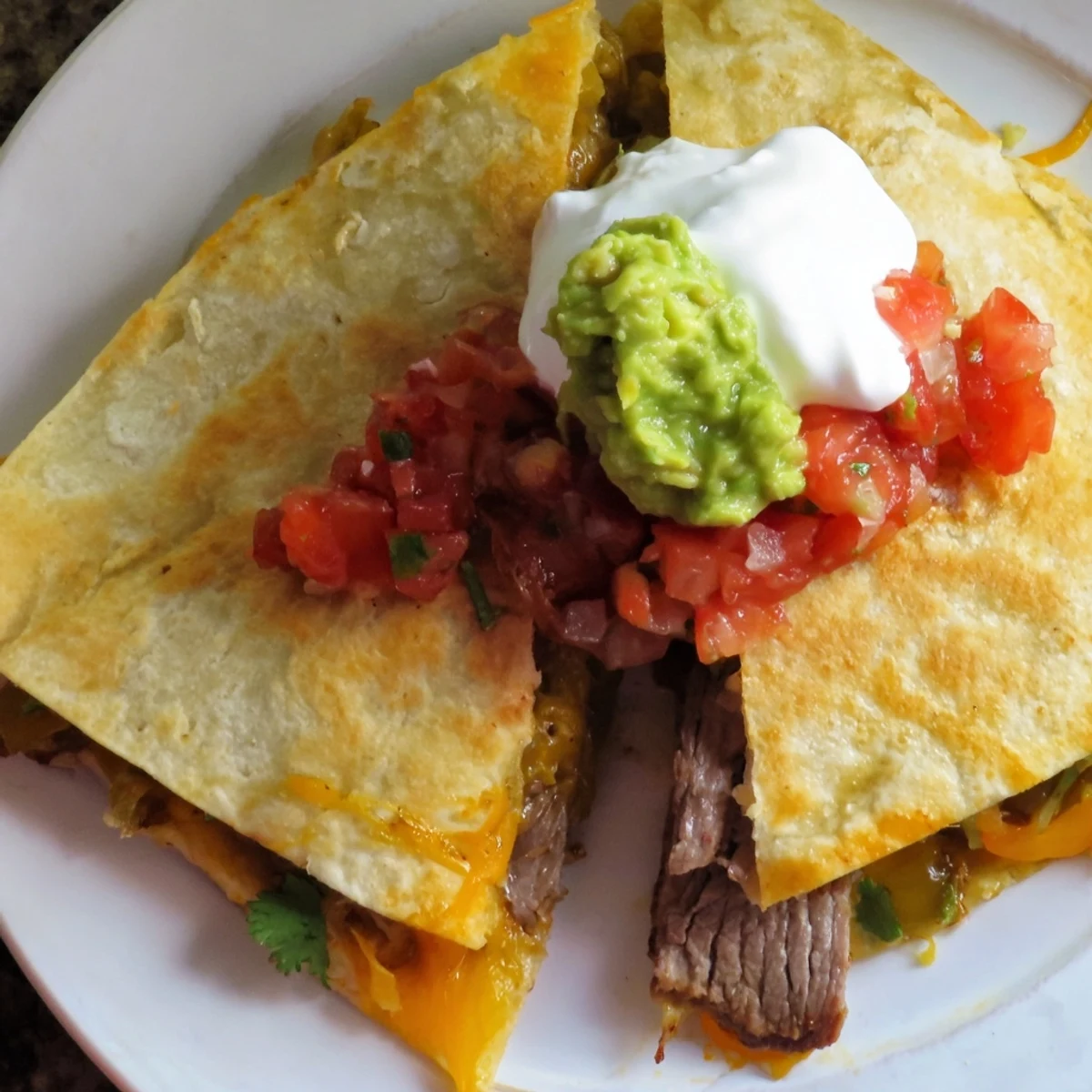 Golden-brown Beef Quesadillas with salsa, guacamole, and sour cream on a rustic plate.