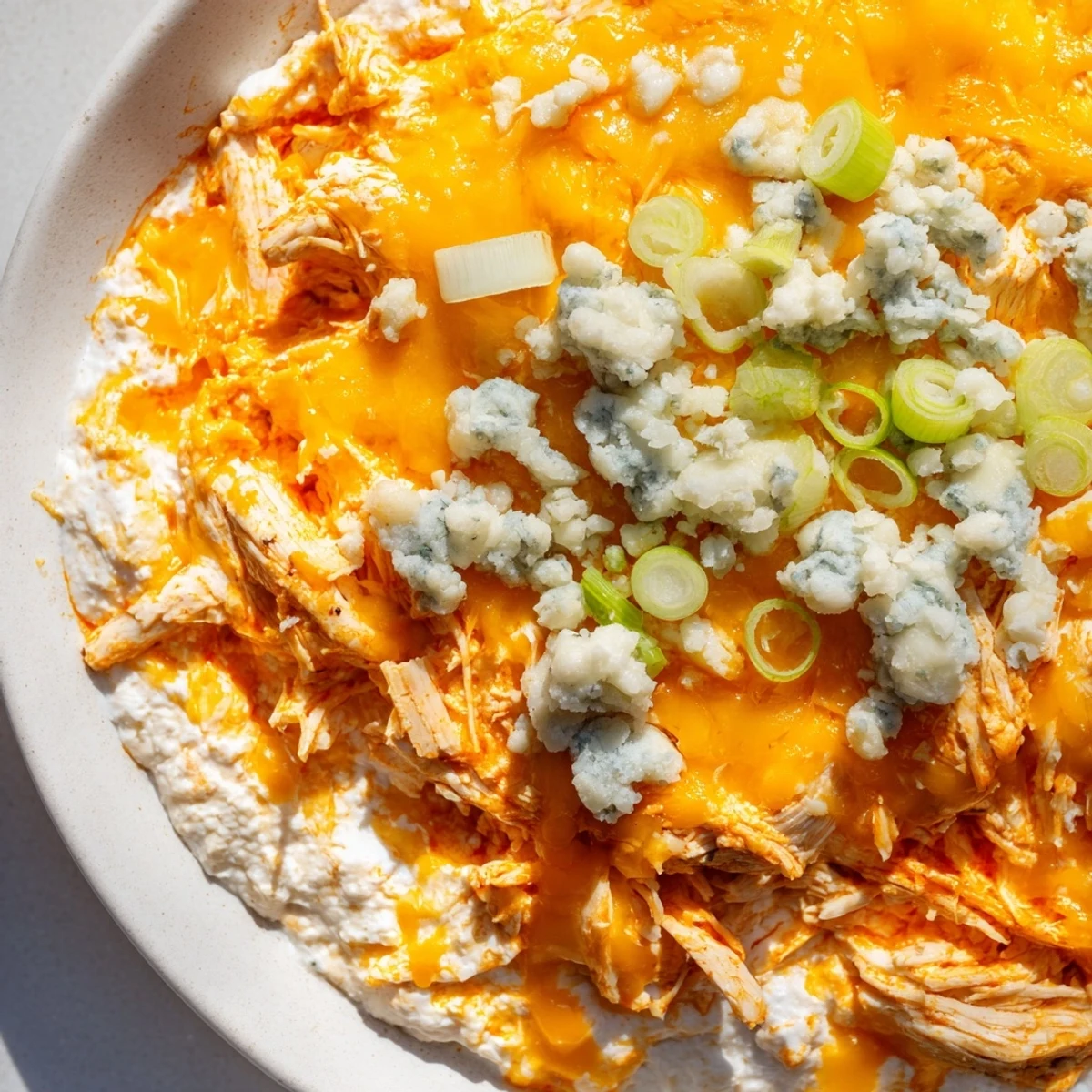 Golden, bubbly Spicy Buffalo Chicken Dip garnished with green onions, served with celery sticks and tortilla chips.