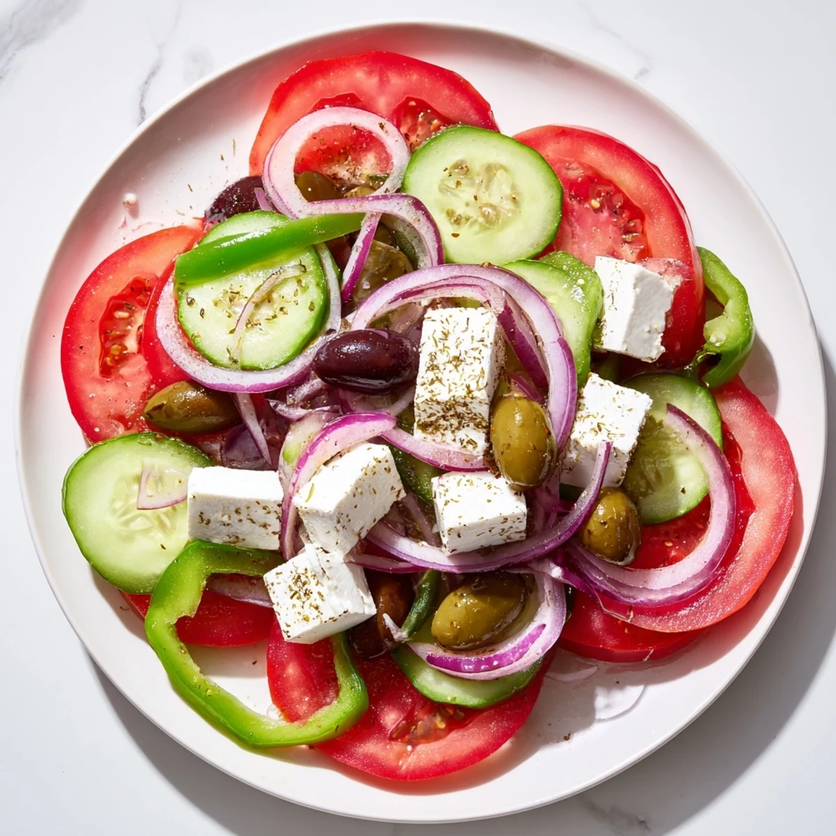 Freshly prepared Greek salad with Kalamata olives and feta, showcasing juicy tomato wedges, cucumber slices, and red onion on a platter.