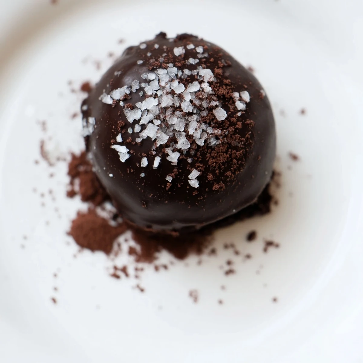 Hand-rolled Romantic Chocolate Truffles with Sea Salt on parchment, sprinkled with flaky salt.