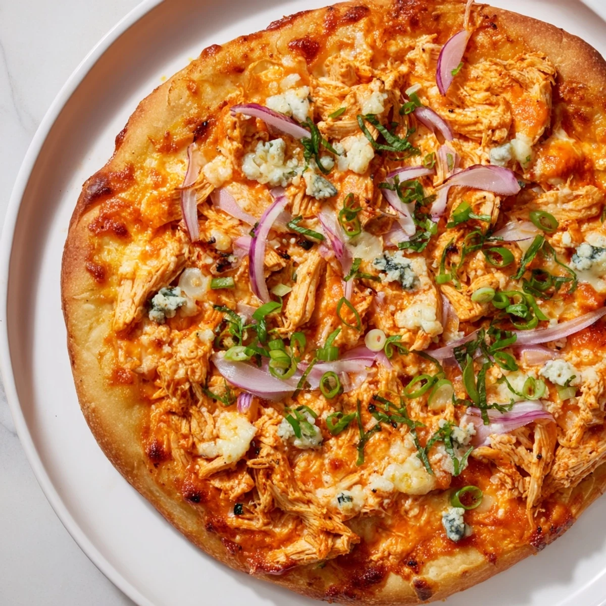 Sliced MVP Buffalo Chicken Pizza with blue cheese crumbles, green onions, and a drizzle of spicy buffalo sauce.