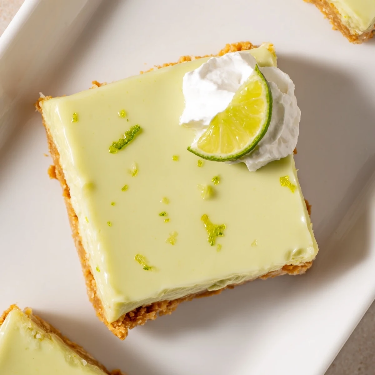 Golden-brown graham cracker crust topped with vibrant green Key Lime Pie Bars garnished with whipped cream.  