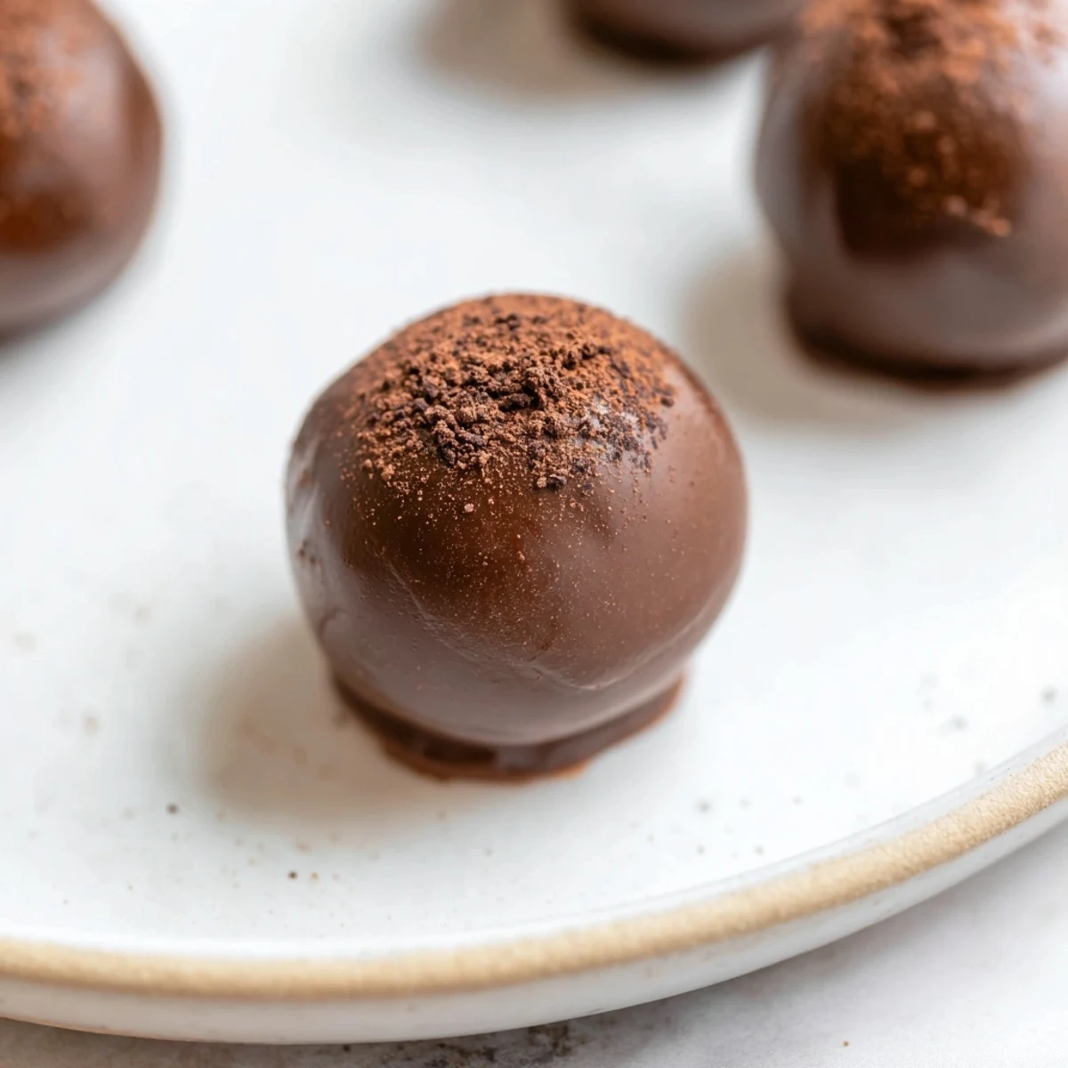 A hand reaching for a decadent Irish Cream Truffle, dusted with cocoa powder, ready to be served.