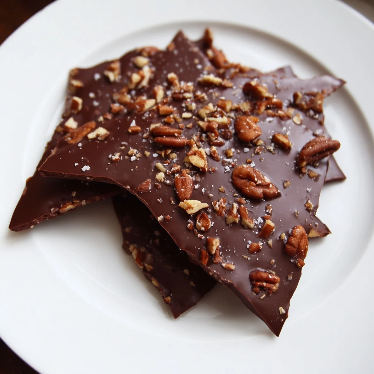 Close-up of Chocolate Covered Matzo Crackers with rainbow sprinkles and chopped pecans on a cooling rack.