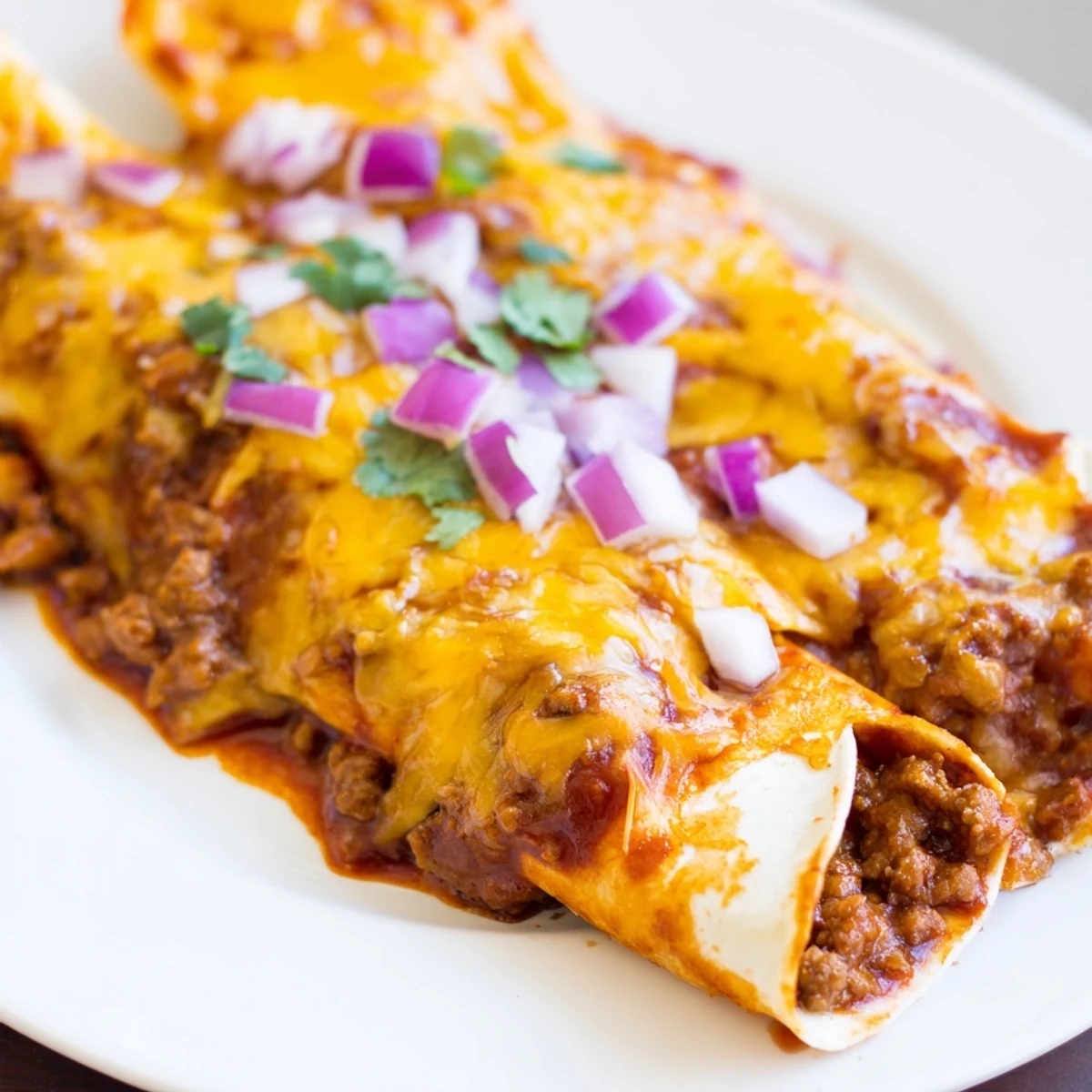 Savory ground beef filling in tender tortillas smothered with rich red enchilada sauce is ready to serve.