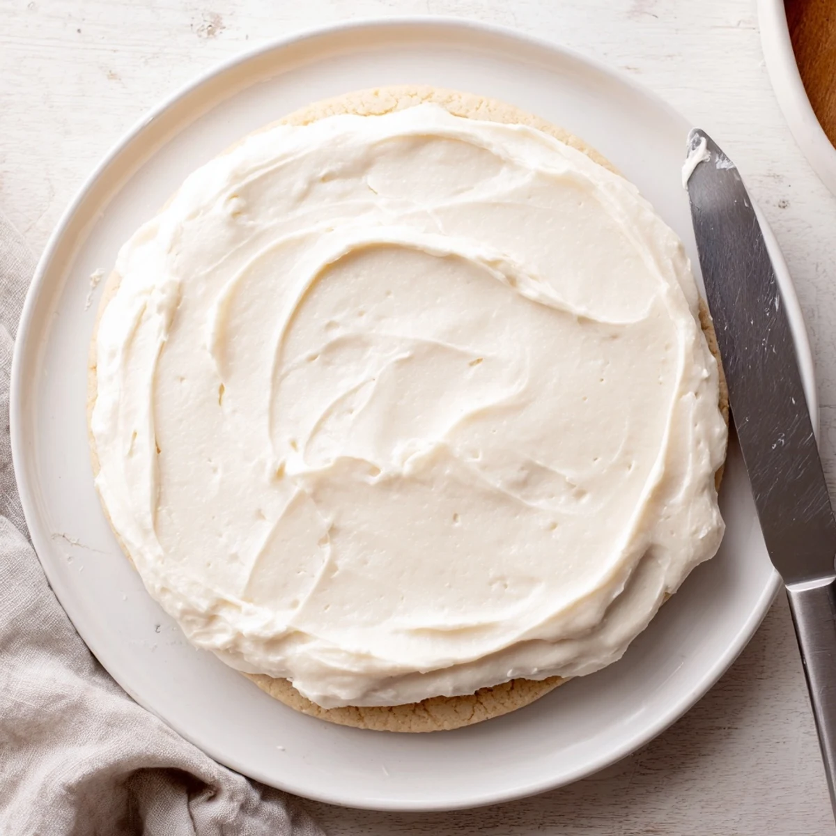 Easy Sugar Cookie Frosting being spread on a sugar cookie, glossy finish with a soft white hue.