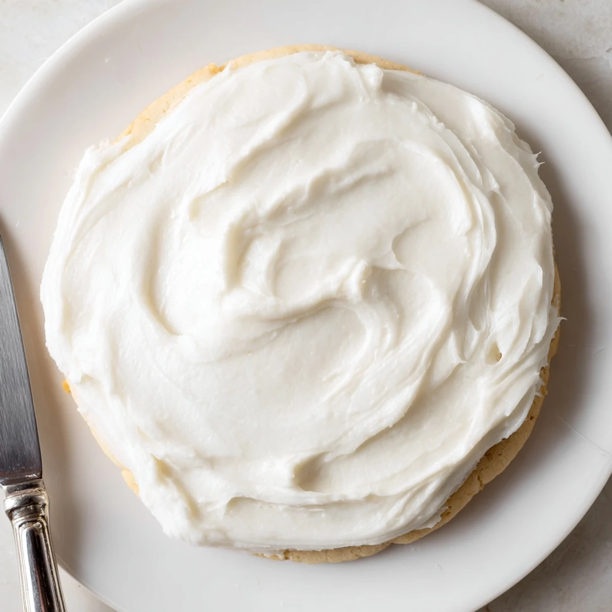 Vibrantly colored Easy Sugar Cookie Frosting in a piping bag, ready to decorate cookies on a baking sheet.