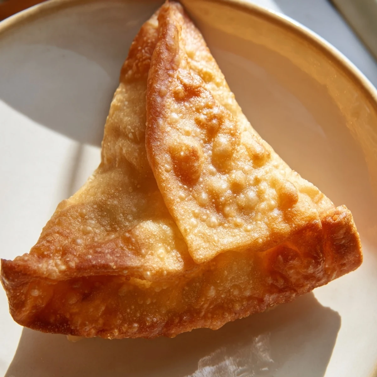 Plated spiced meat sambusas with steam rising, served beside a small bowl of tangy dipping sauce.