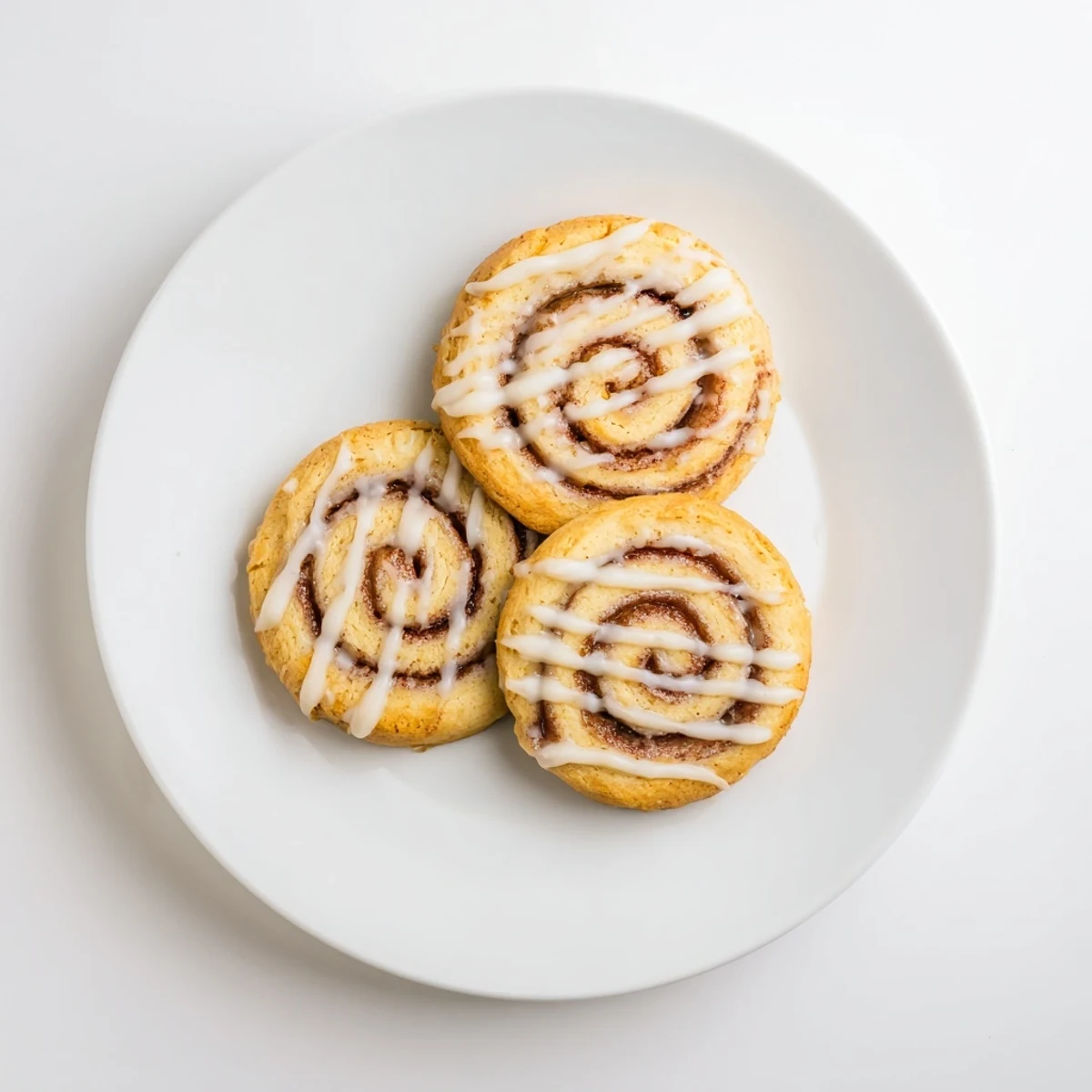 A close-up of Cinnamon Roll Cookies shows their soft texture, buttery crumbs, and sweet glaze dripping down the sides.