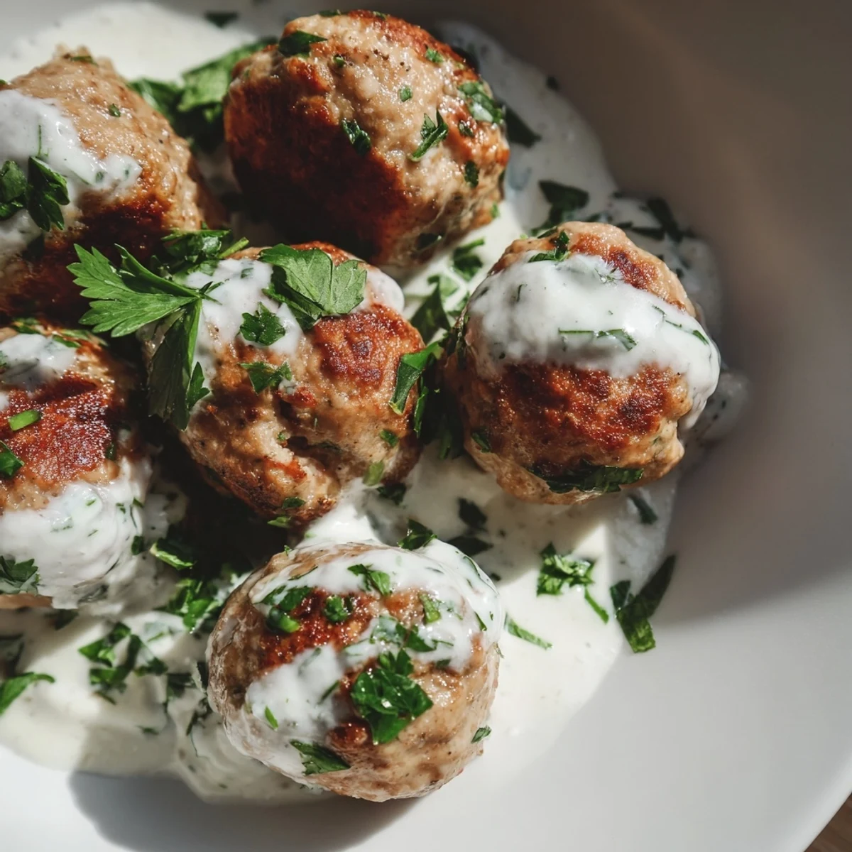 Freshly cooked Chicken Kofta nestled beside a creamy white garlic yogurt dip, sprinkled with dill for a vibrant presentation.