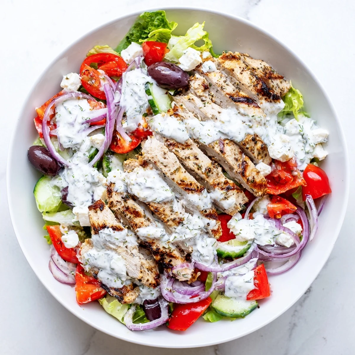 Freshly prepared Tzatziki Chicken Salad features juicy grilled chicken, crisp cucumber, and crumbled feta cheese on a bed of greens, perfect for a light lunch.
