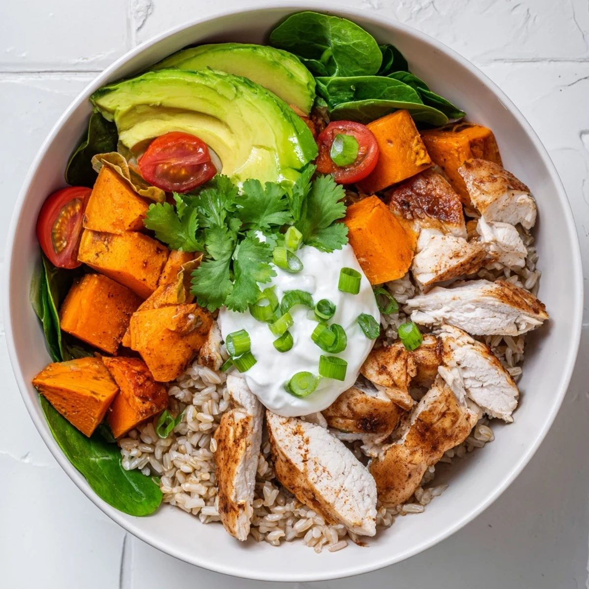 Overhead view of a Wholesome Chicken Sweet Potato Rice Bowl, featuring juicy chicken, roasted sweet potatoes, and vibrant toppings like cherry tomatoes and cilantro.