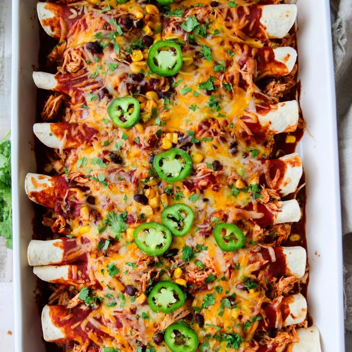 Golden-baked Chicken Enchiladas with melted cheese and fresh cilantro on a plate, served with sour cream.
