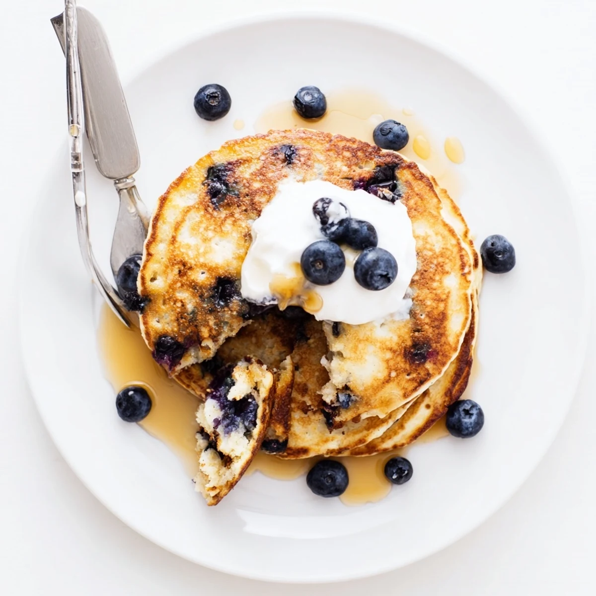 Golden Greek Yogurt Blueberry Pancakes stacked high, golden edges, juicy berries popping, ready for maple syrup drizzle.