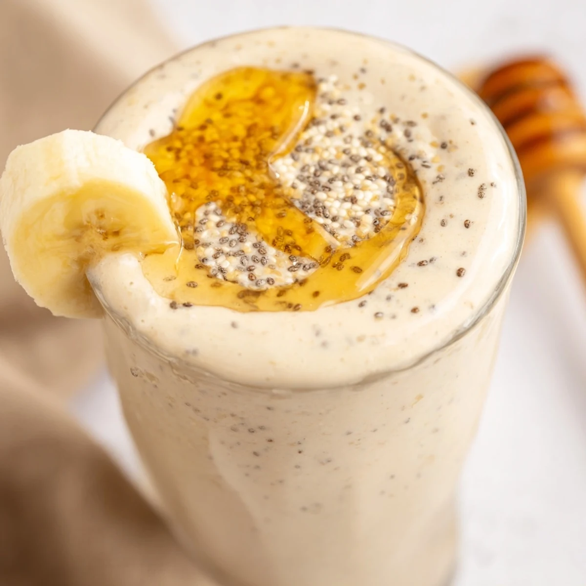 Creamy Greek yogurt banana smoothie poured into glasses topped with fresh banana slices and a sprinkle of cinnamon