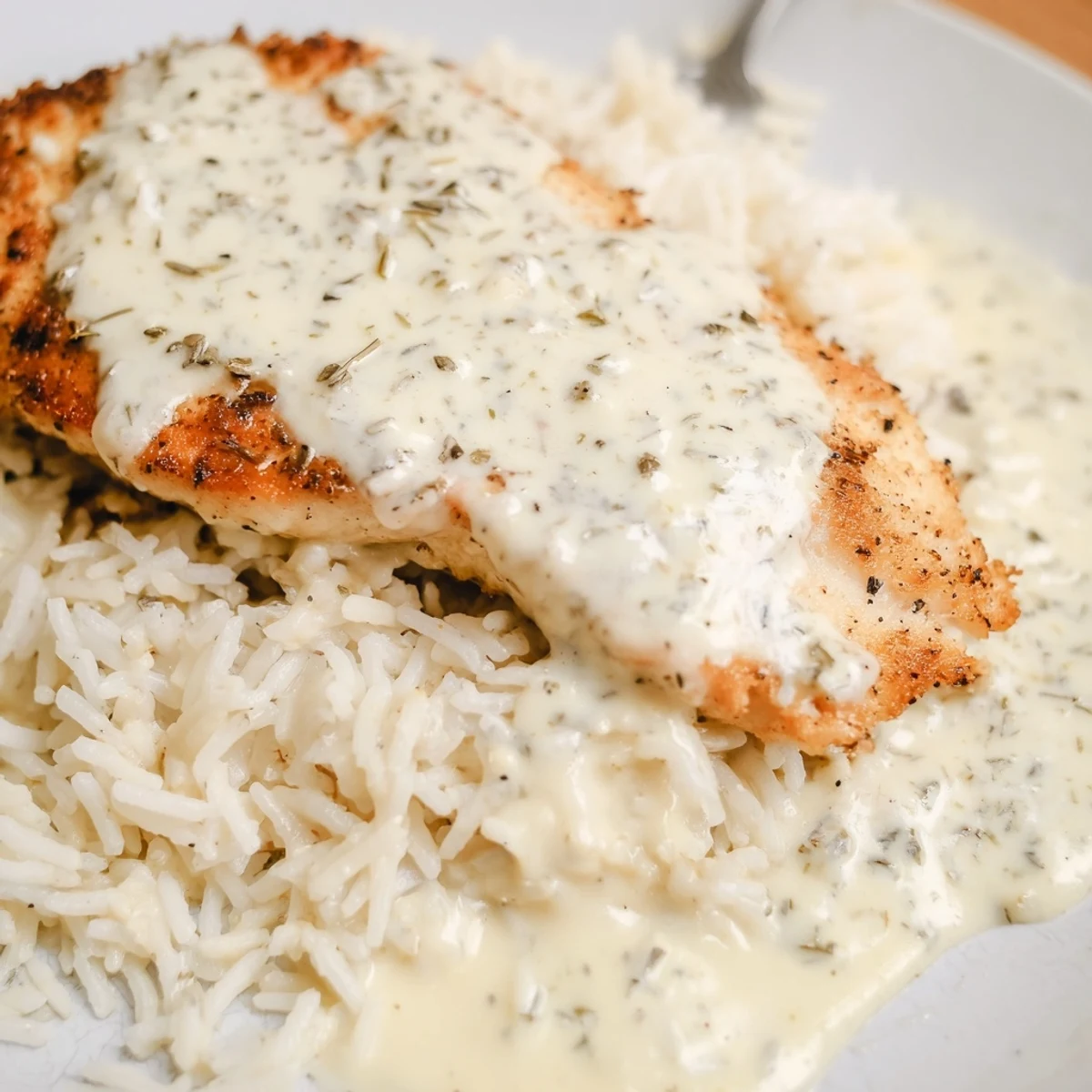 Tender smothered chicken drizzled with creamy mushroom sauce served atop steaming rice