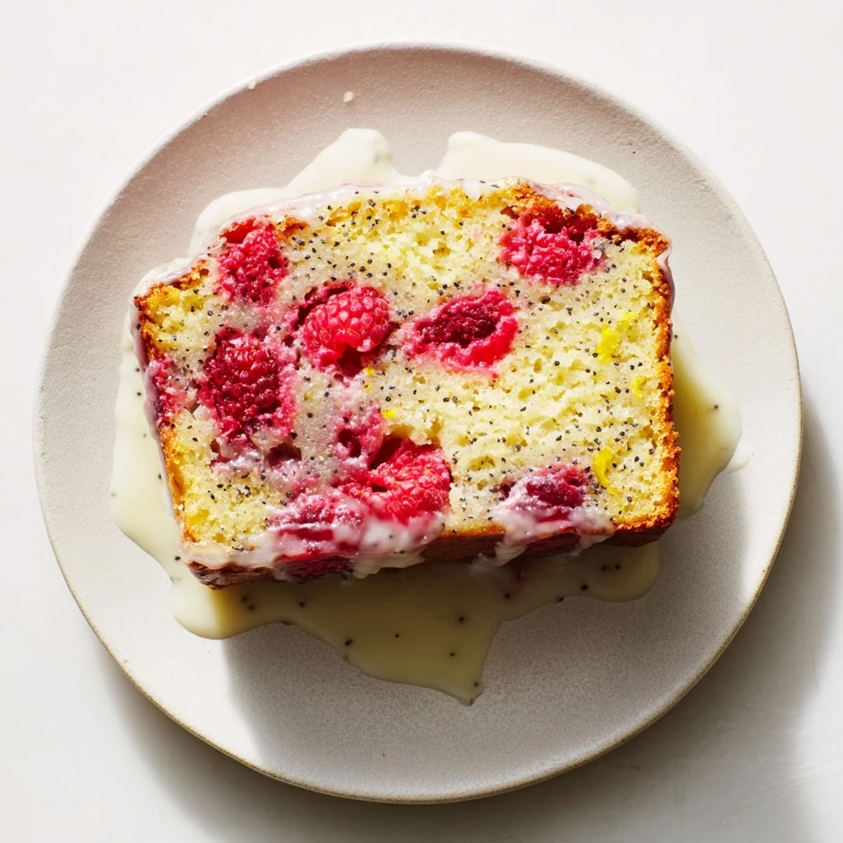 Moist slice of raspberry lemon poppyseed loaf cake showing bright red berry pockets and yellow crumb