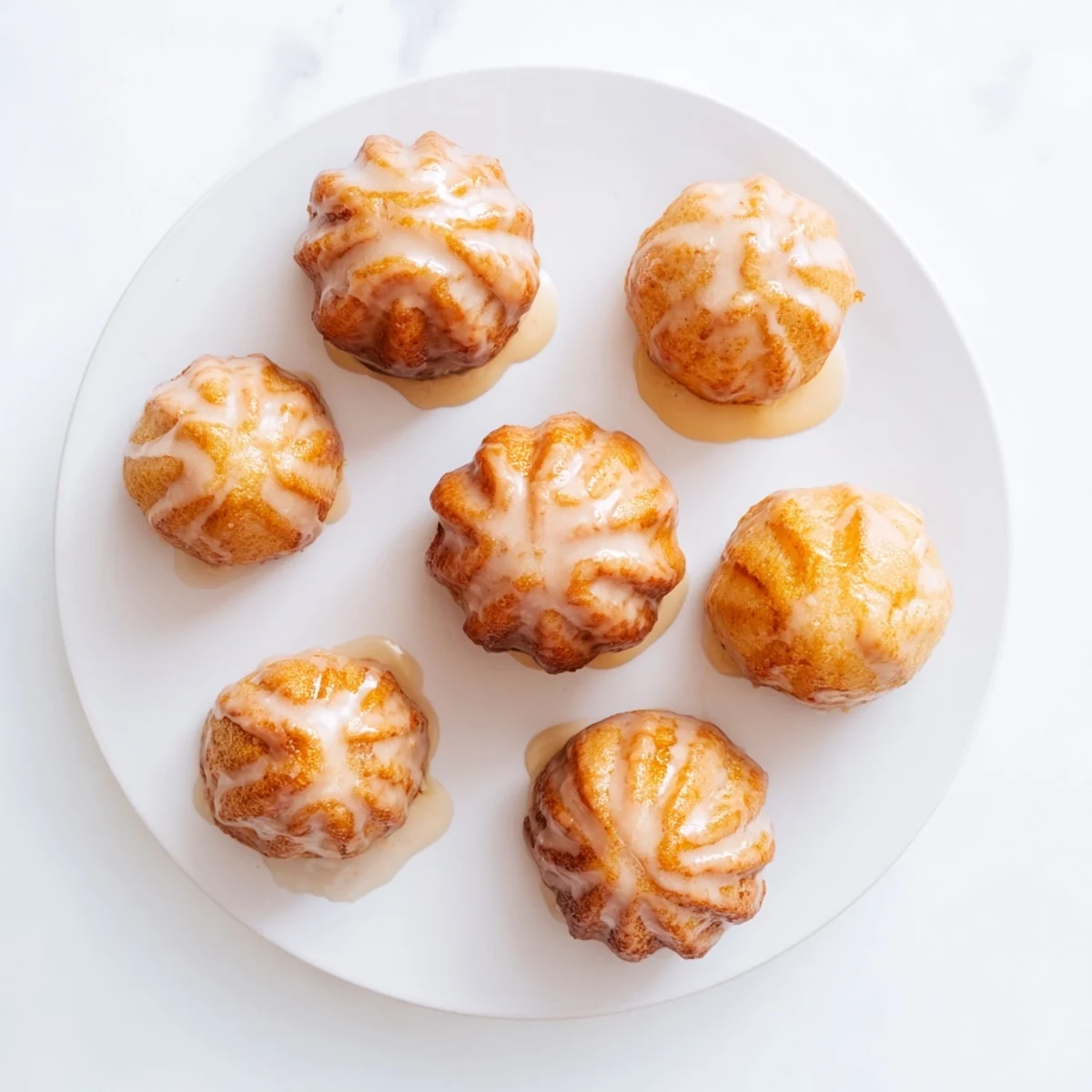 Golden maple pumpkin mochi donuts topped with sweet glaze on a white wire rack