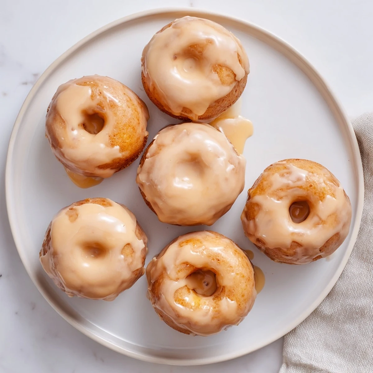 Chewy gluten-free pumpkin mochi donuts drizzled with maple icing and dusted cinnamon