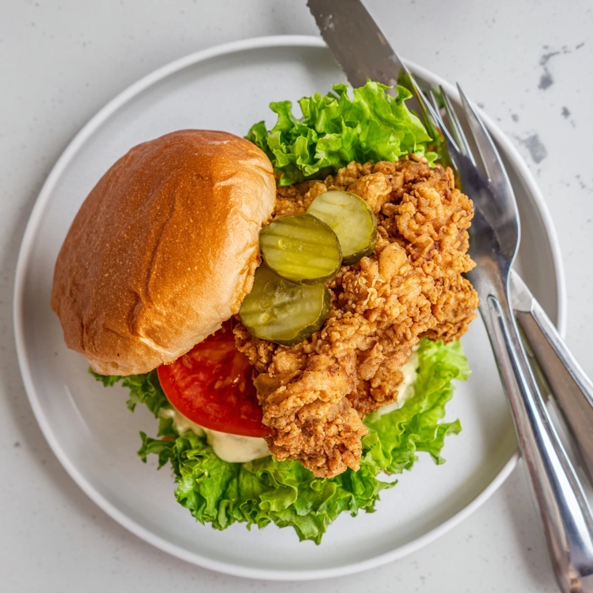 Crispy fried chicken burger featuring juicy thigh meat topped with tangy pickles and spicy mayonnaise