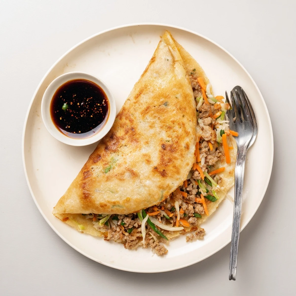 Folded pancake revealing savory pork, vegetables, and scrambled eggs inside a golden wrapper