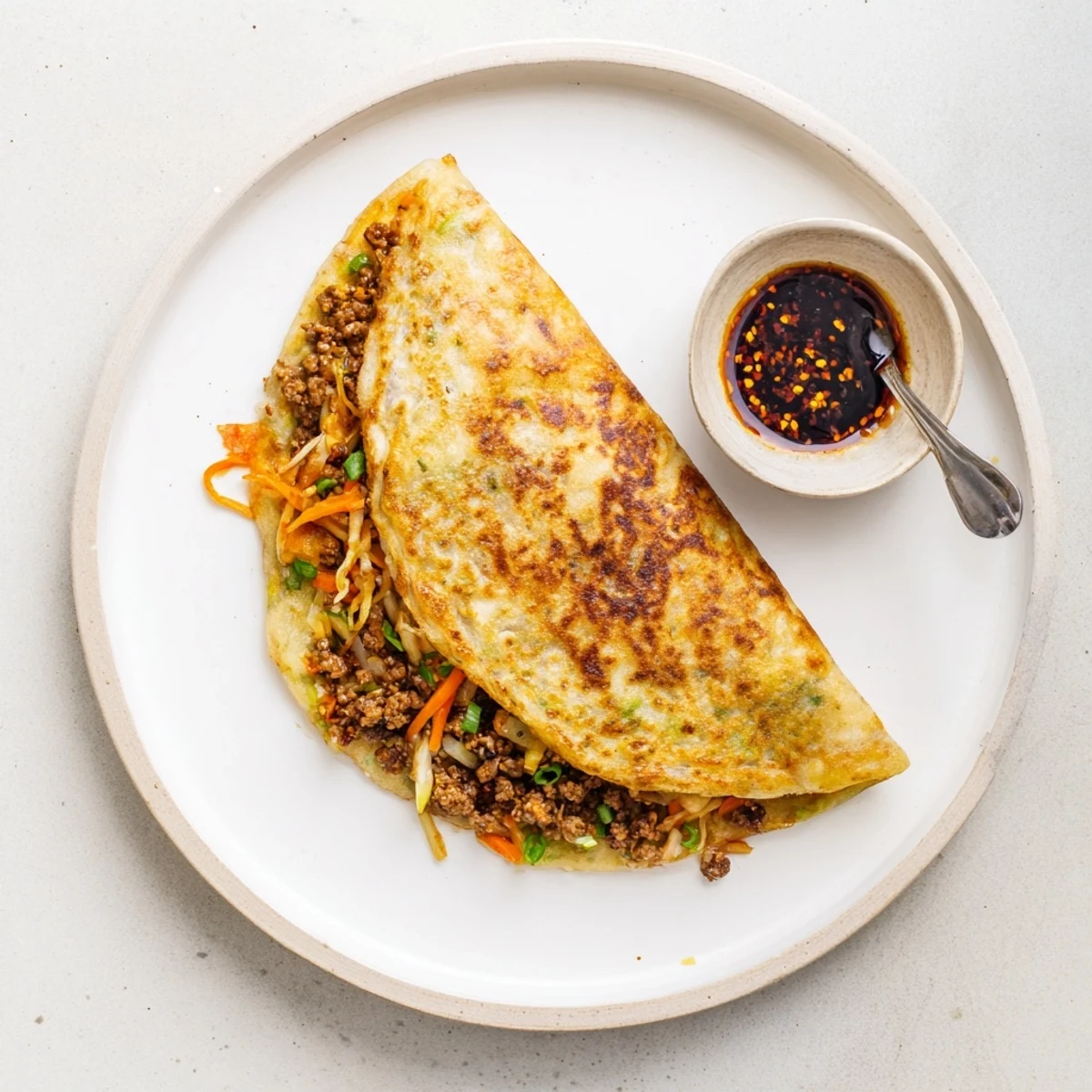 Hot stuffed breakfast pancakes plated with dipping sauce, showing meat and egg filling spilling out