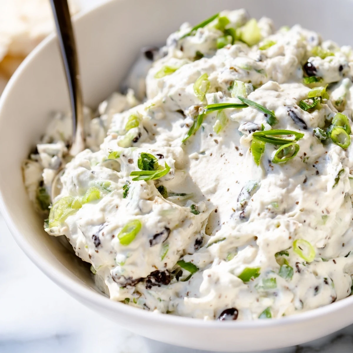 Creamy homemade olive dip topped with fresh parsley and served with crispy crackers for entertaining