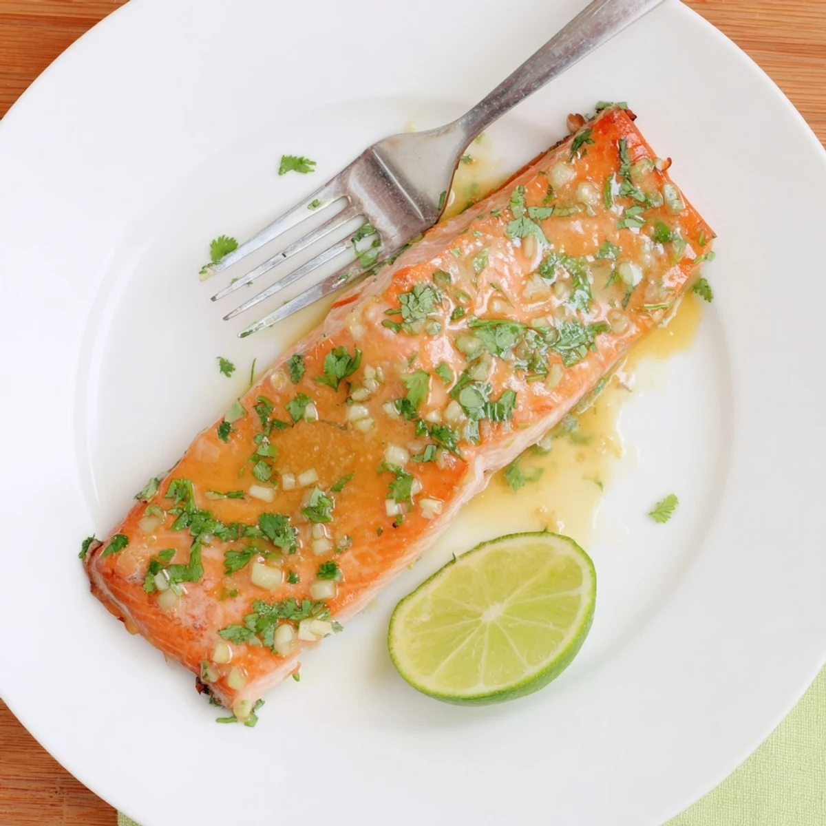 Golden baked salmon fillet glazed with honey lime garlic butter sauce on a white plate