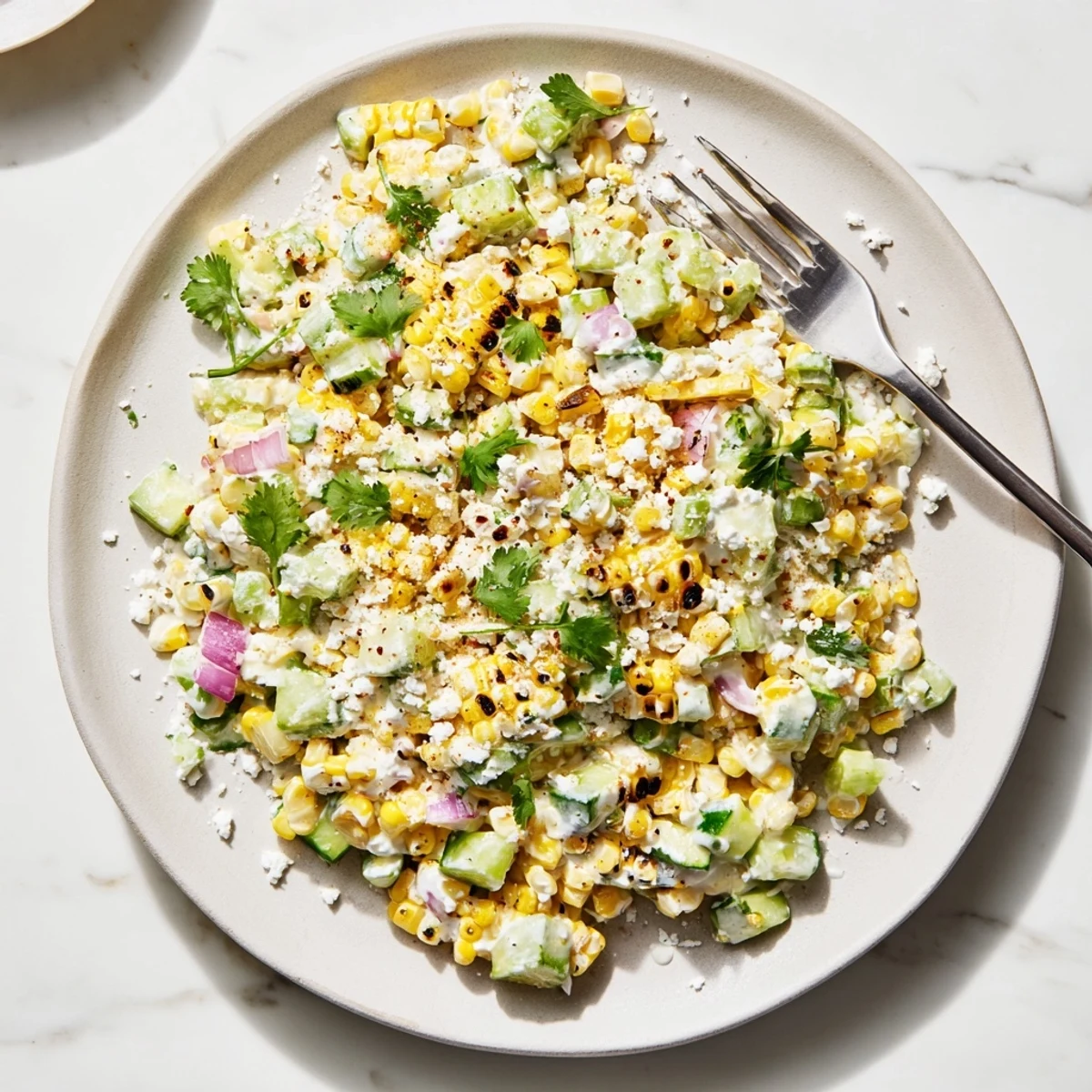 Summer side dish of grilled corn and cucumber salad tossed in tangy street corn spices and sour cream dressing