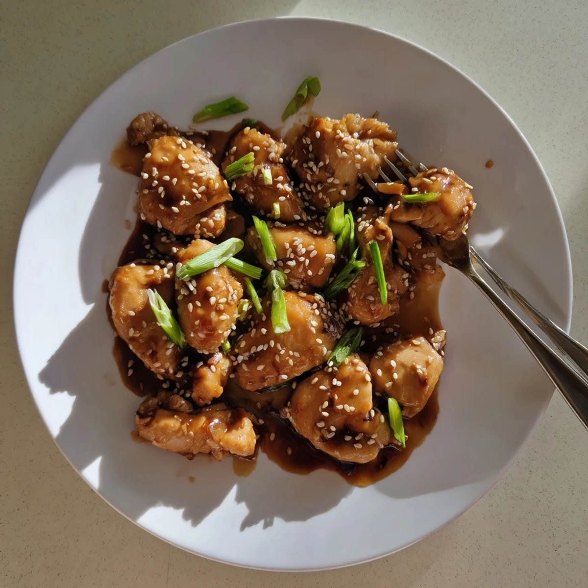 Shredded chicken pieces coated in thick homemade teriyaki sauce with sesame seed garnish