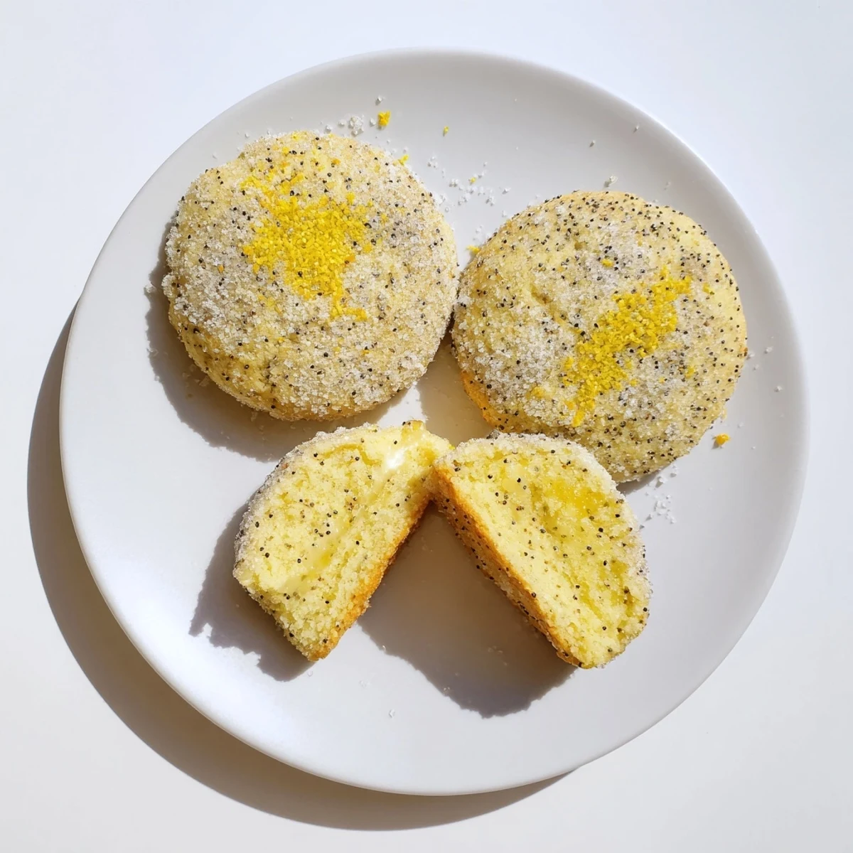 Sugared lemon poppy seed cheesecake cookies stacked high with visible poppy seed specks