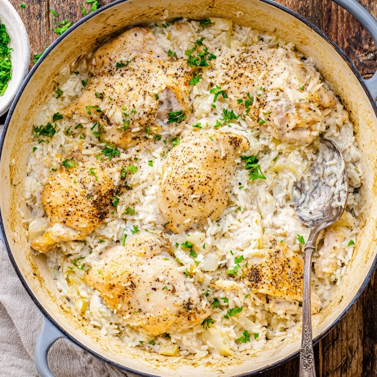 Creamy one pot angel chicken rice dinner bubbling in a dutch oven with fresh parsley garnish