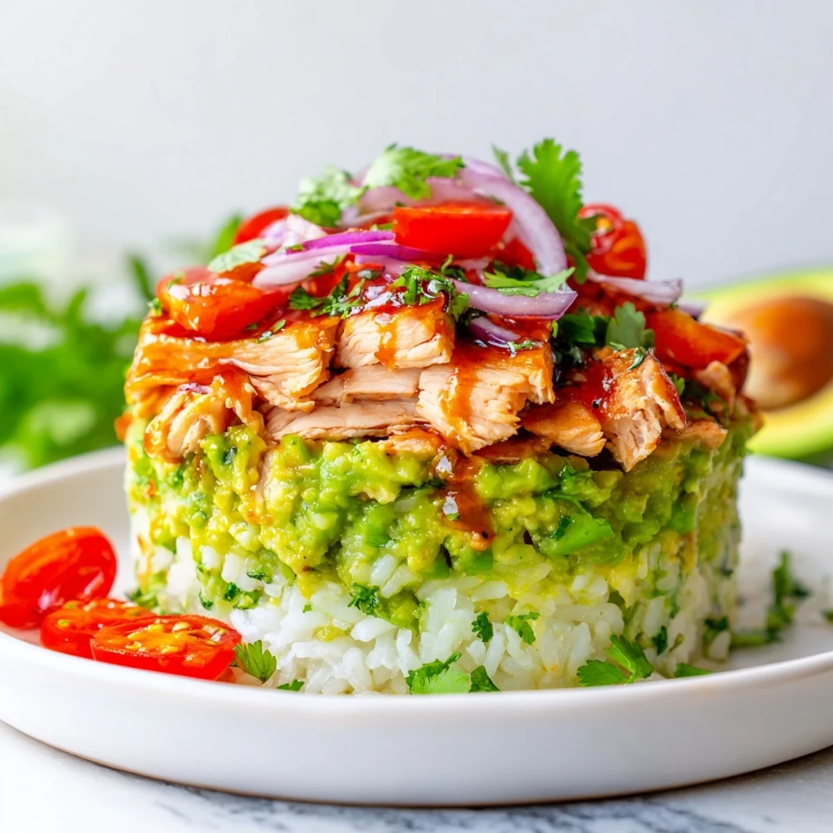 Honey lime chicken avocado rice stack with grilled sliced chicken layered over fluffy white rice and creamy diced avocado garnished with fresh cilantro and red onion