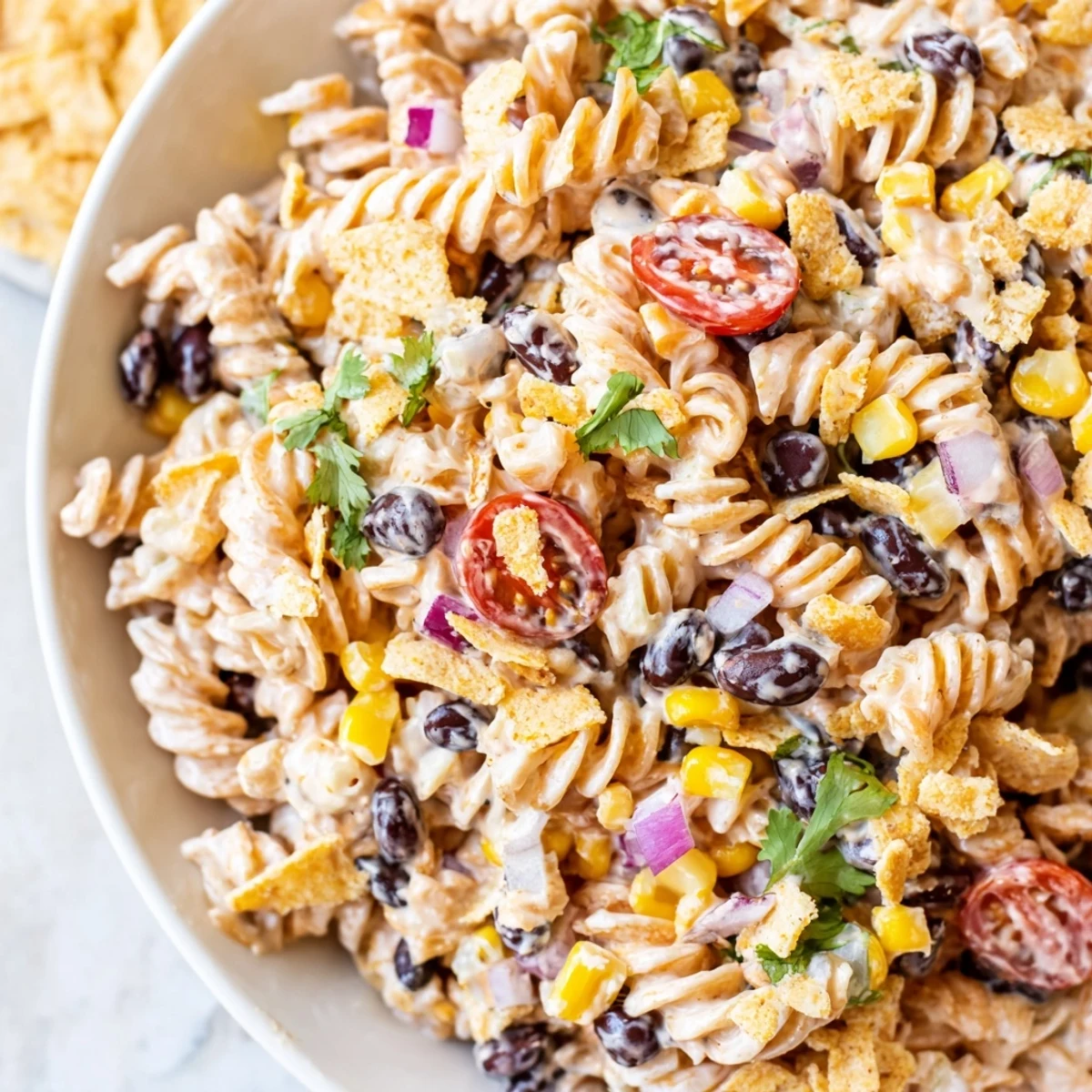 Colorful taco pasta salad in a serving bowl with tomatoes corn and creamy dressing