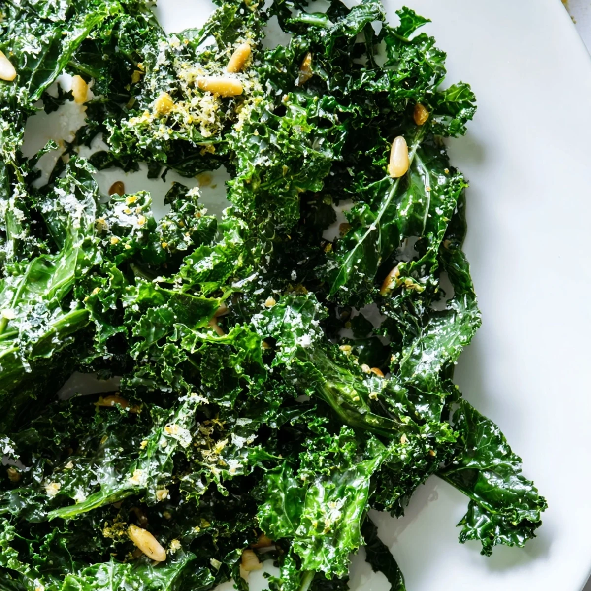 Fresh garlic lemon Parmesan kale salad topped with shaved cheese in a white bowl