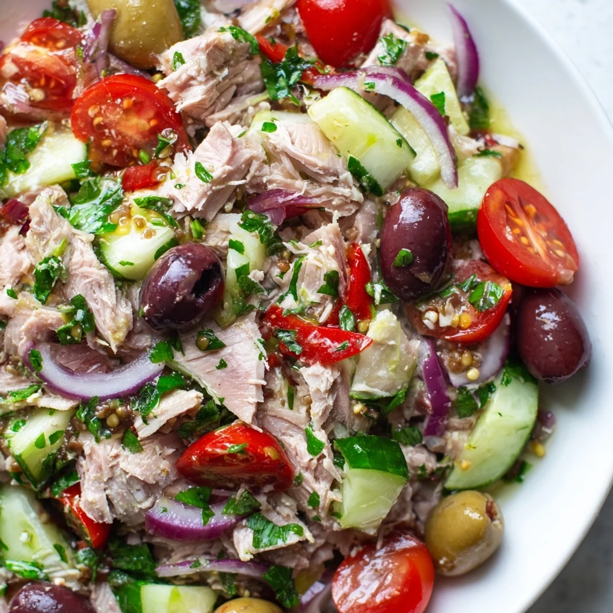 Fresh Mediterranean tuna salad in a bowl with cherry tomatoes, olives, and bright herbs