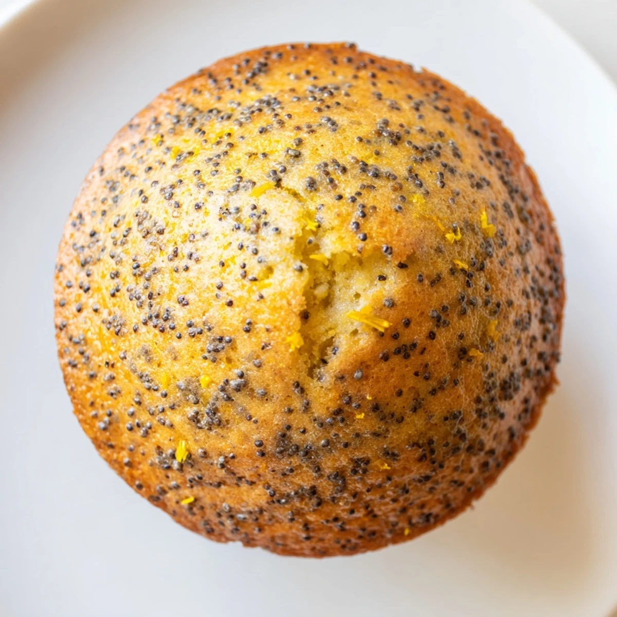Golden lemon poppy seed muffins with domed tops fresh from the oven on a cooling rack.