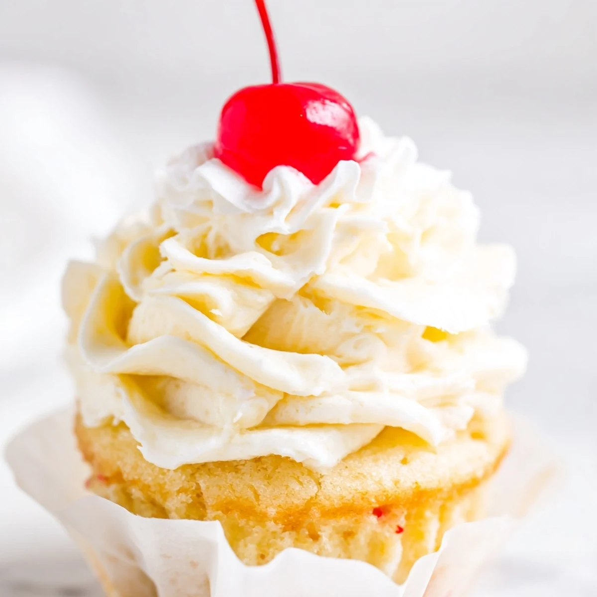 Moist banana milkshake cupcakes topped with creamy vanilla frosting and garnished with bright red cherries
