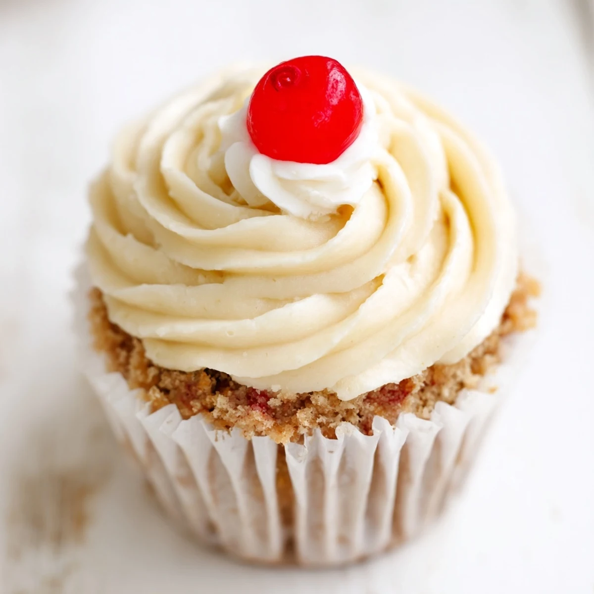 Golden banana milkshake cupcakes with fluffy buttercream swirls served on a rustic white ceramic plate