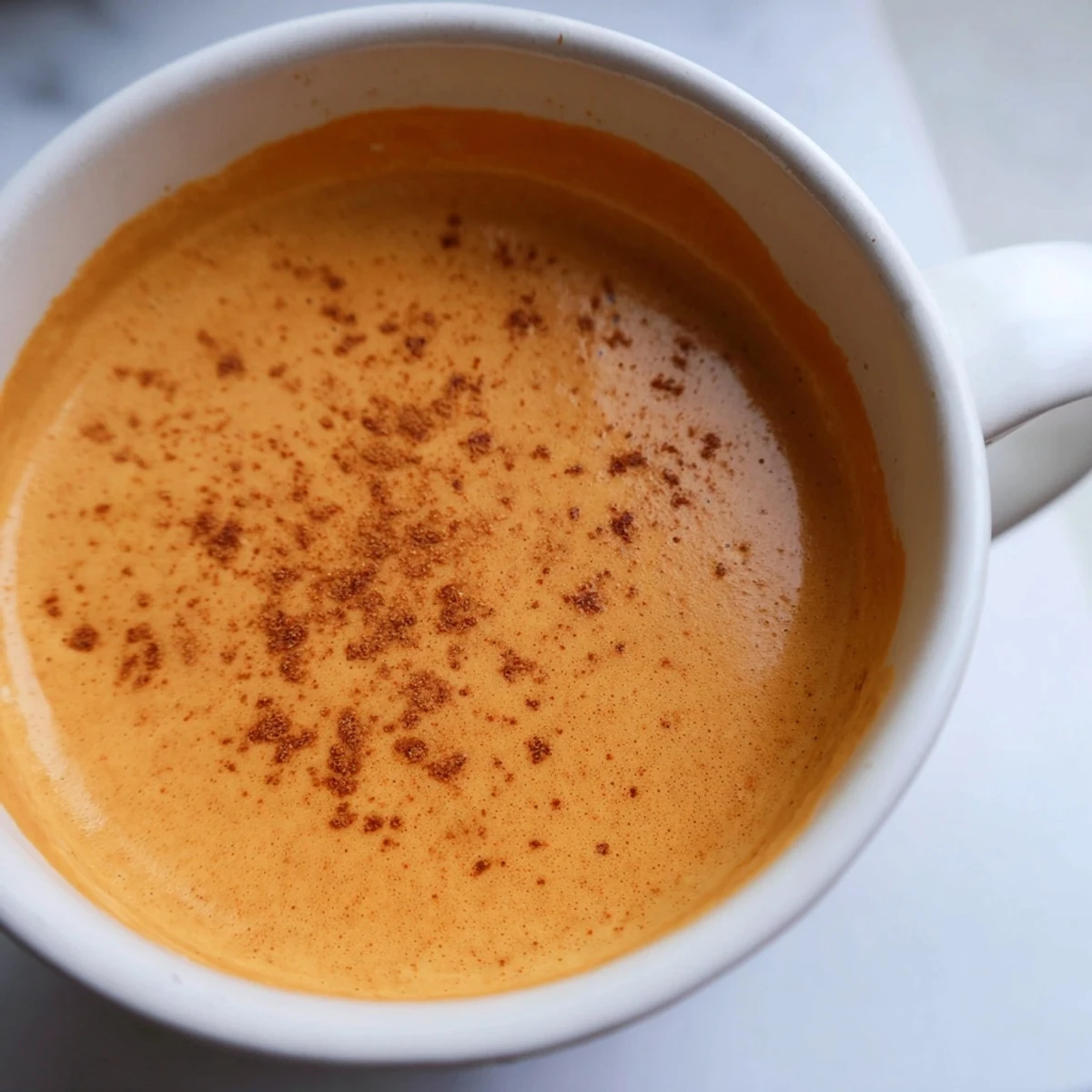 Creamy Goguma Latte topped with cinnamon in a cozy mug on a rustic autumn table